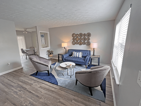 A living room with a blue couch and a grey armchair.