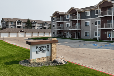 A sign for Plantation Hunters Run in front of apartment buildings.