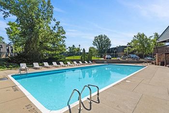 a swimming pool with chaise lounge chairs next to a building