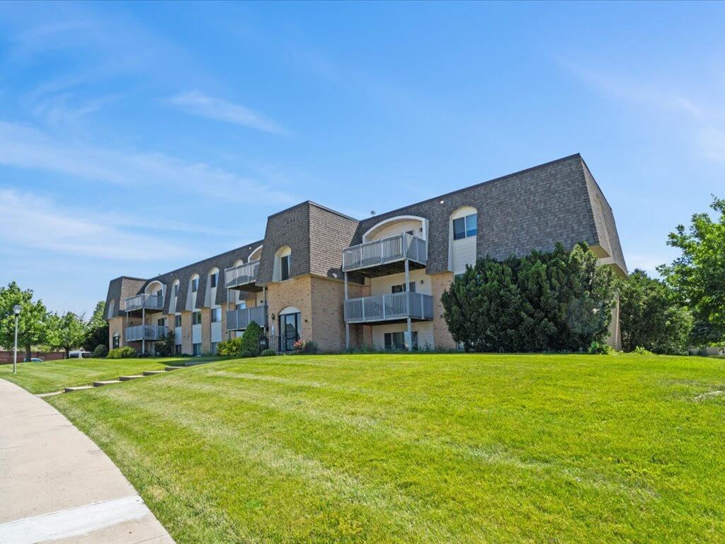 a large brick apartment building with a green lawn