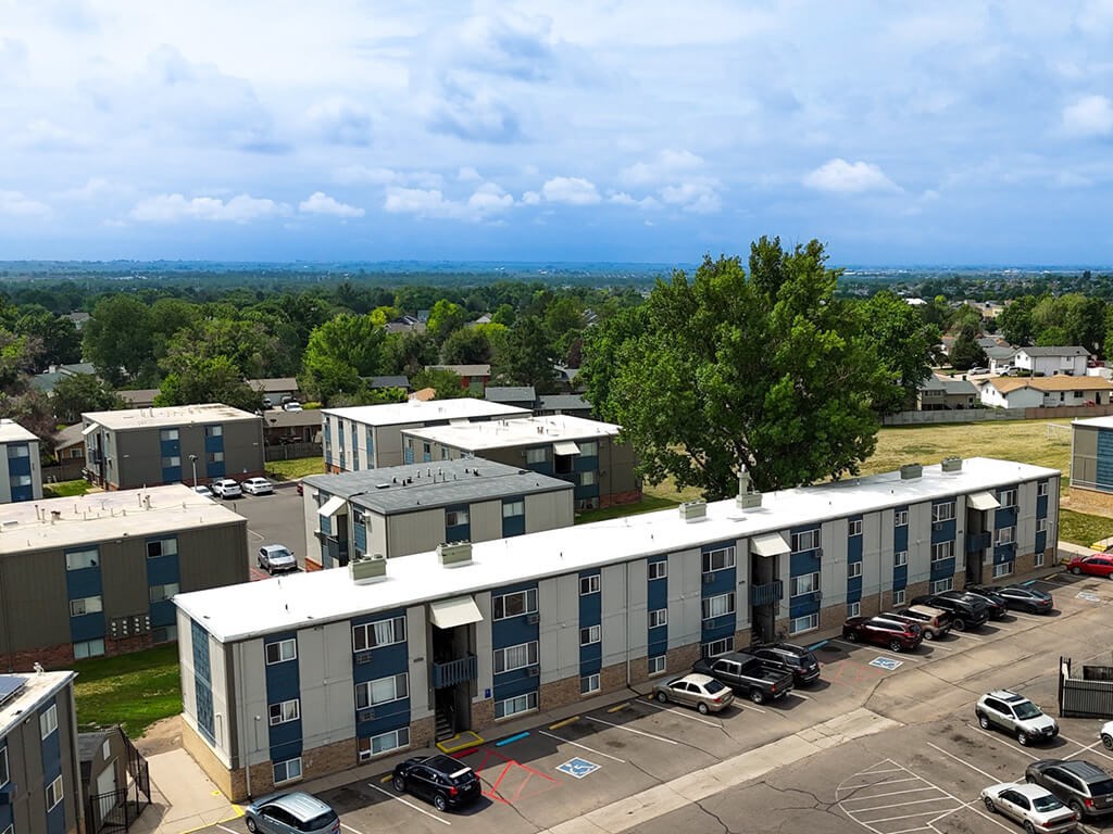 A view of a parking lot with cars and apartment buildings.