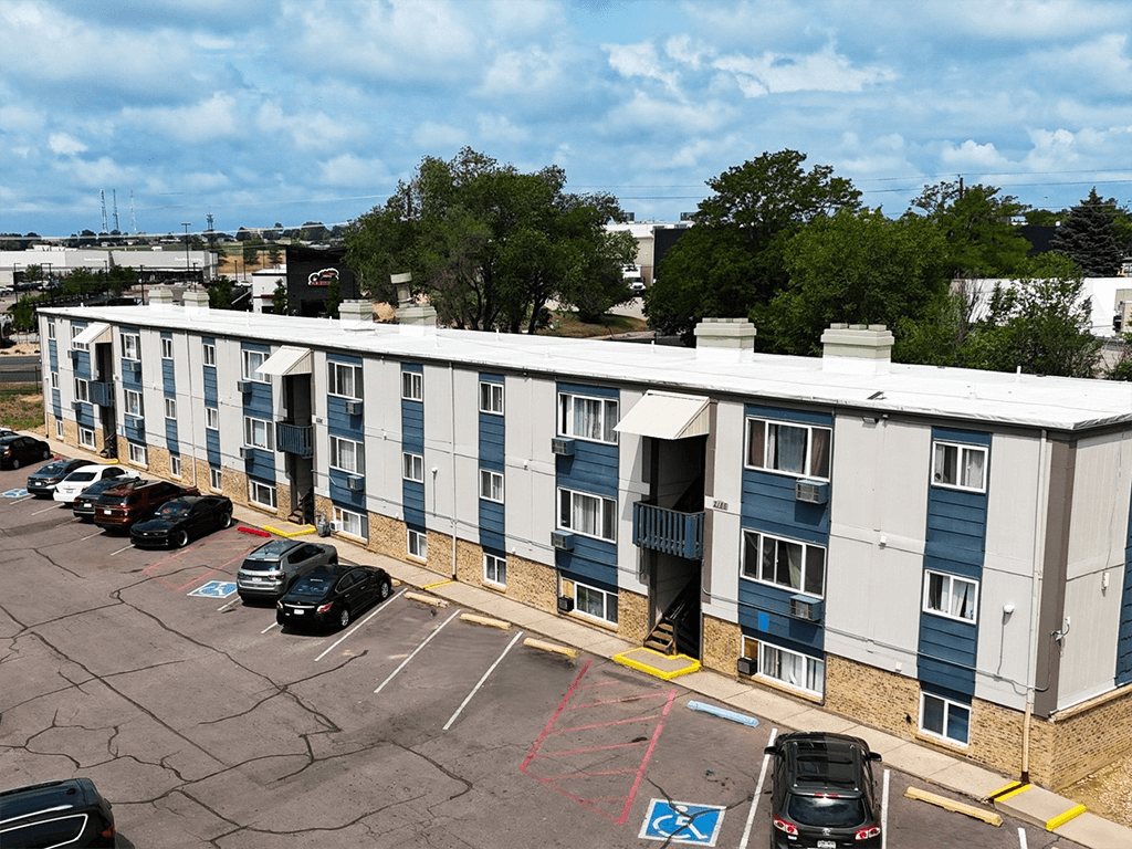 A parking lot in front of a multi-story apartment building.