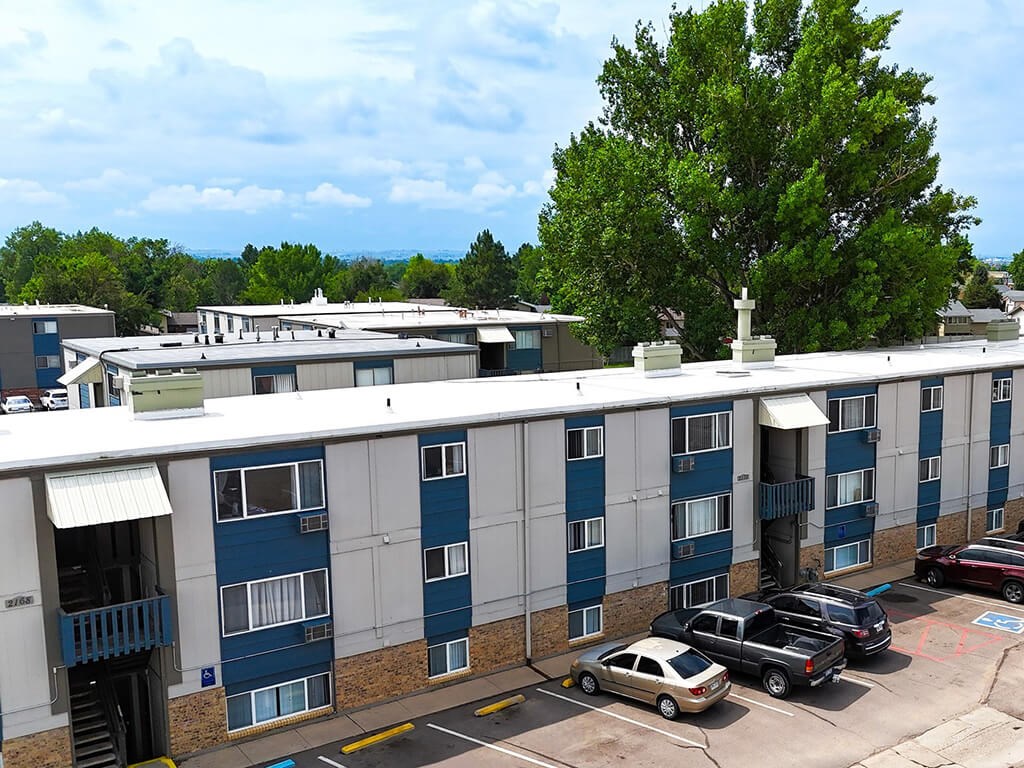 A parking lot with cars and a building with blue doors.