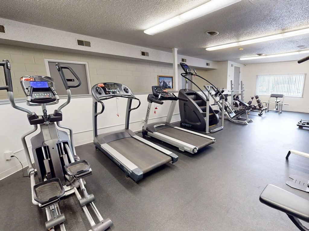 A gym with treadmills, elliptical machines, and other exercise equipment.