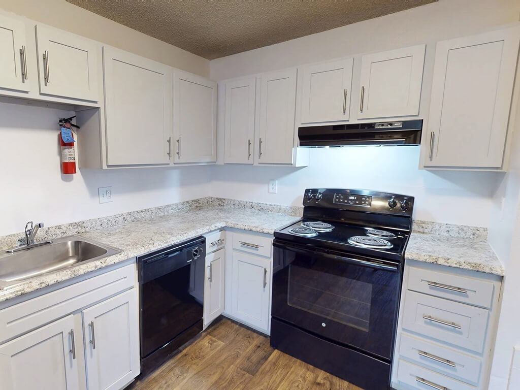 A kitchen with white cabinets and a black stove top oven.