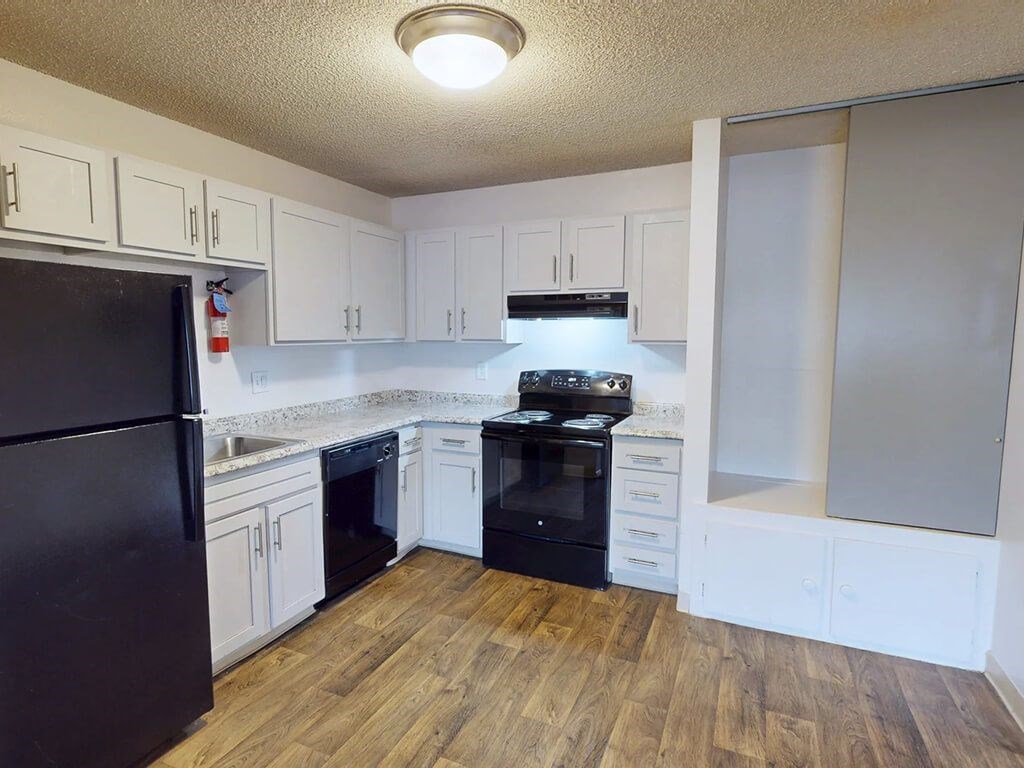 A kitchen with black appliances and white cabinets.