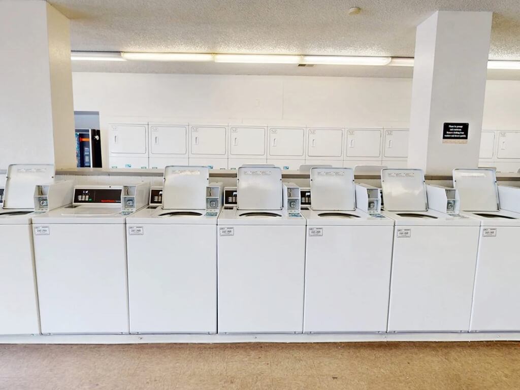 A series of white washing machines are lined up in a row.