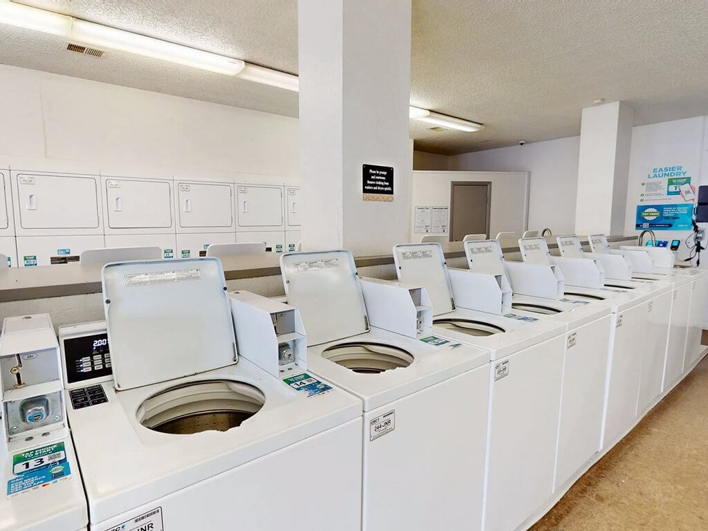 A row of washing machines are lined up in a laundromat.