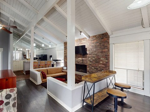 A modern open plan living and kitchen area with a brick fireplace.