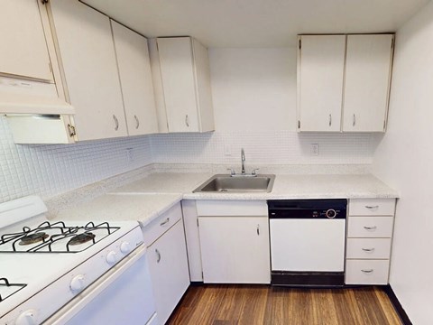 A kitchen with white cabinets and a white stove.