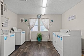a laundry room with three machines and a window