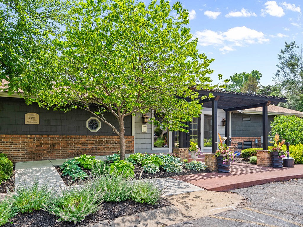 the front of a house with a porch and a tree