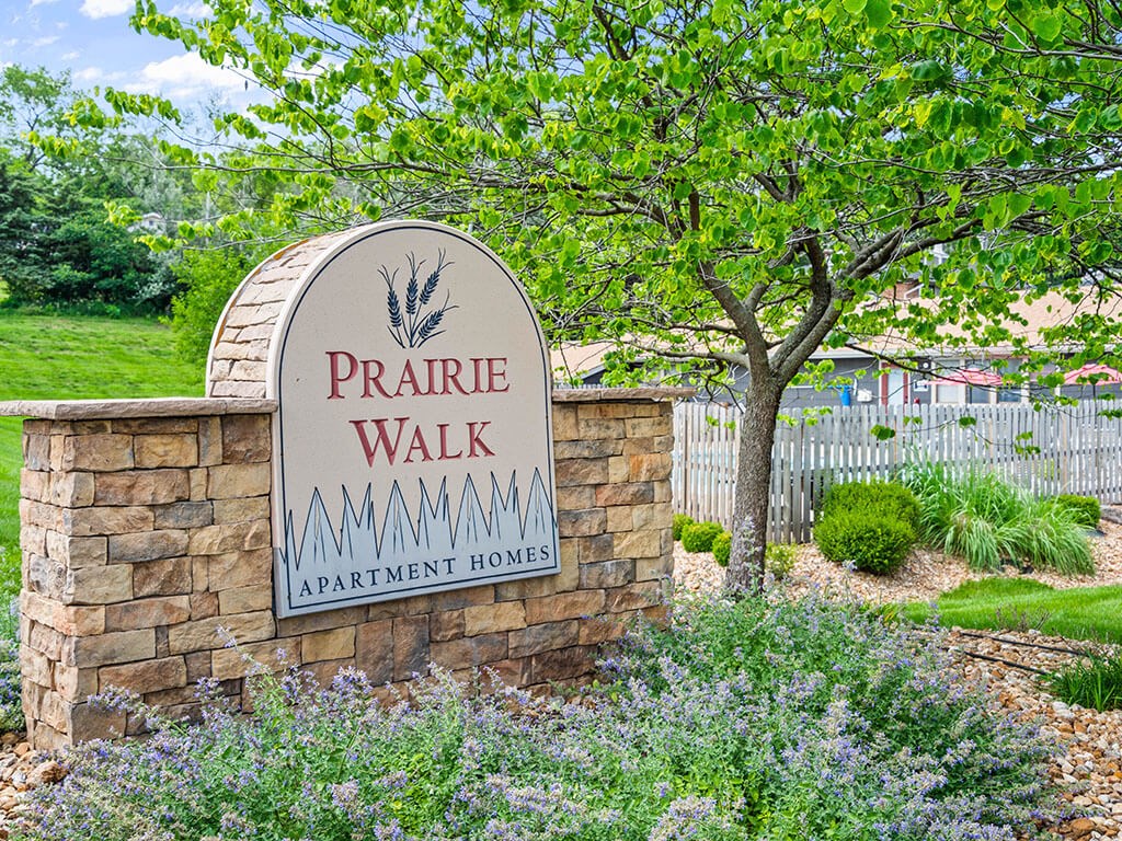 a welcome sign for Prairie Walk apartments