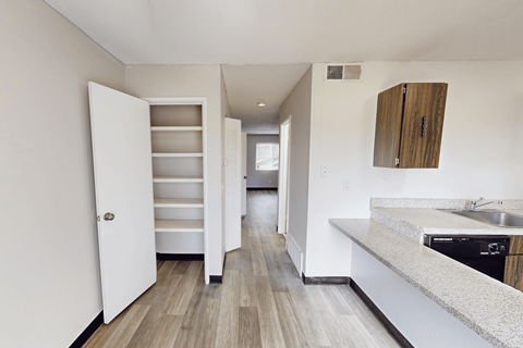A kitchen with a white counter top and a white door.
