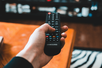 A hand is holding a Samsung remote control.