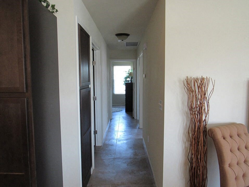 a hallway with a chair and a vase in a room