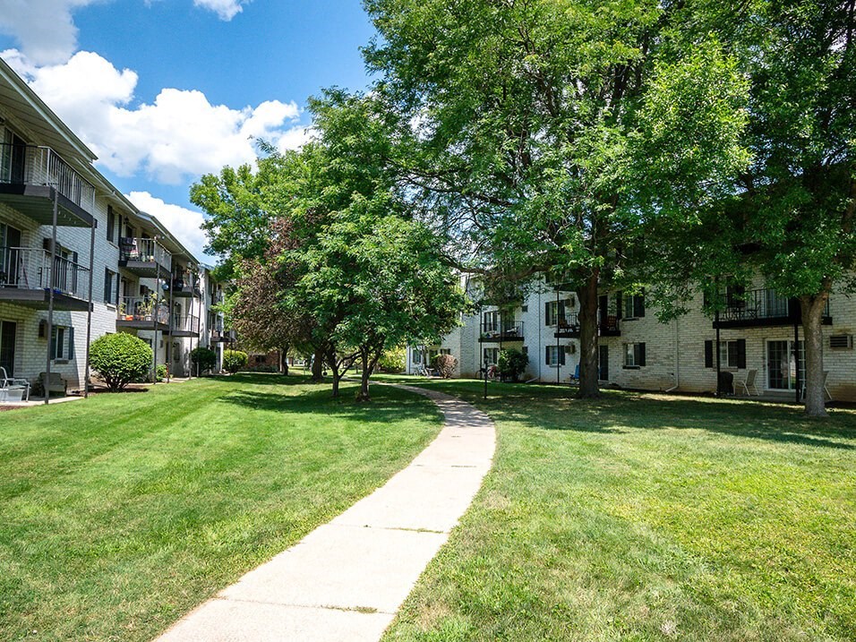 sidewalk with large shady trees at rivers edge apartments