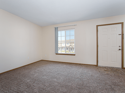 an empty living room with a door and a window