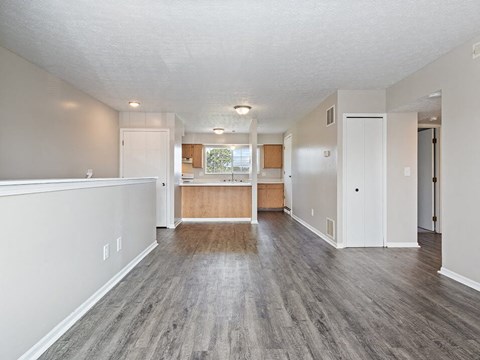 A spacious room with wood flooring and white walls.