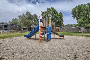 a playground with slides and chairs in a park