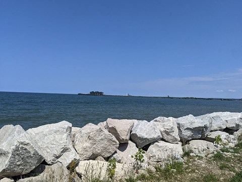 A rocky shoreline with a body of water and a distant island.