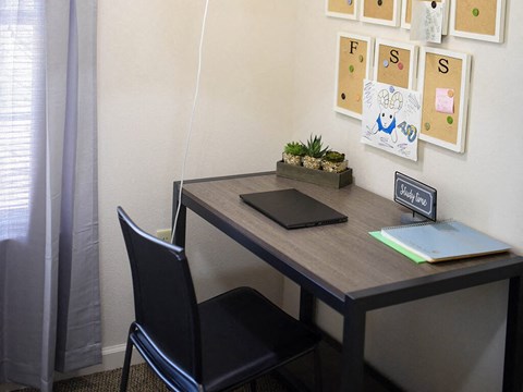 a desk with a laptop and a chair in a room
