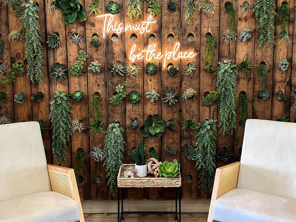 this must be the place neon wedding sign against a wooden wall with succulent plants