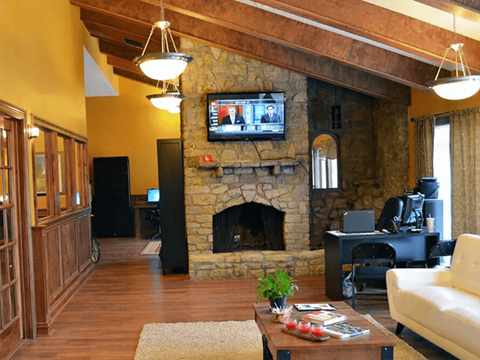 a living room with a stone fireplace and a tv above it