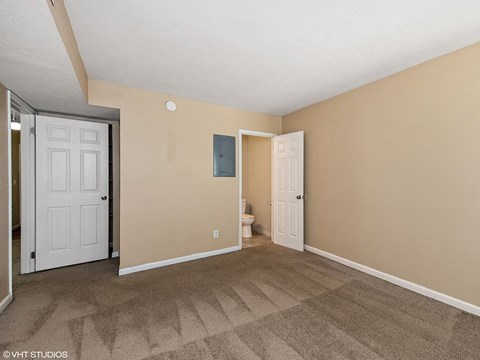 a carpeted living room with a door to the bathroom