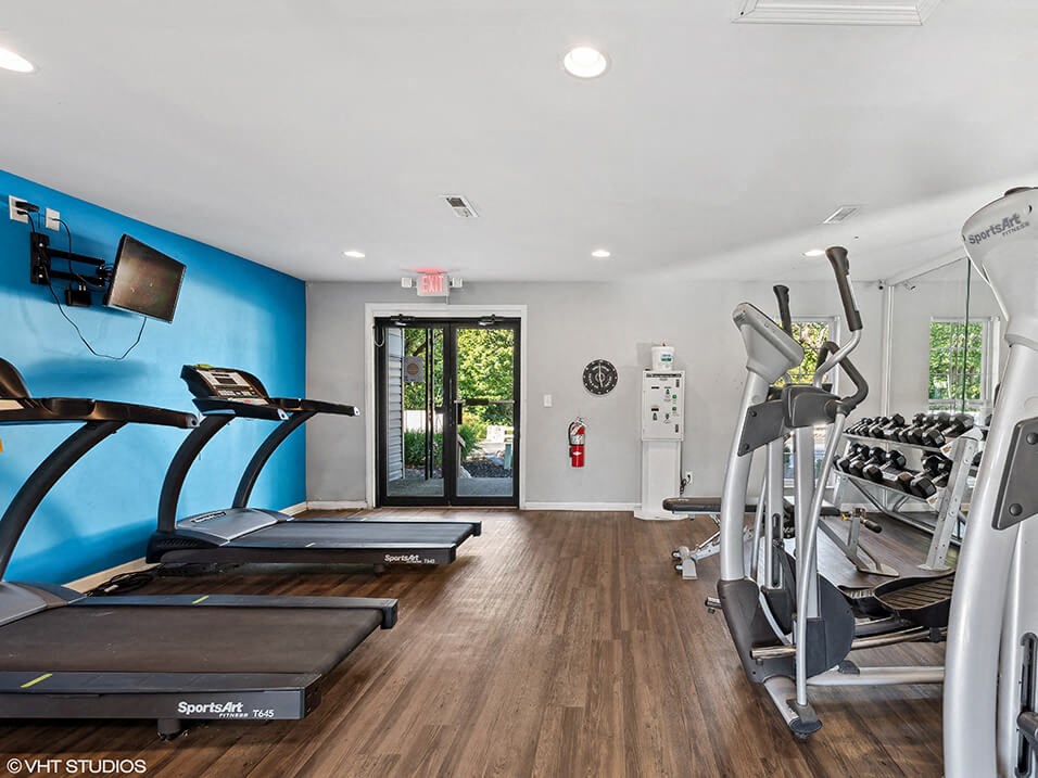 a gym with cardio equipment and a blue wall