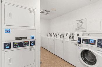 a row of washing machines and dryers in a laundry room