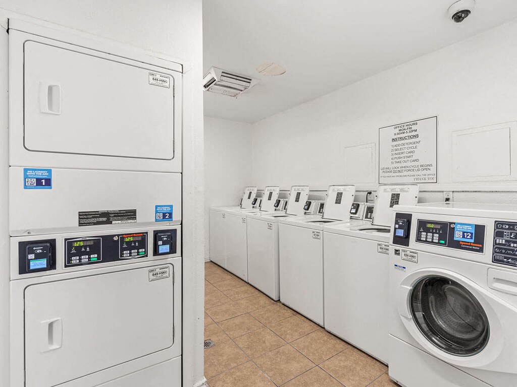 a row of washers and dryers in a laundry room with washer machines