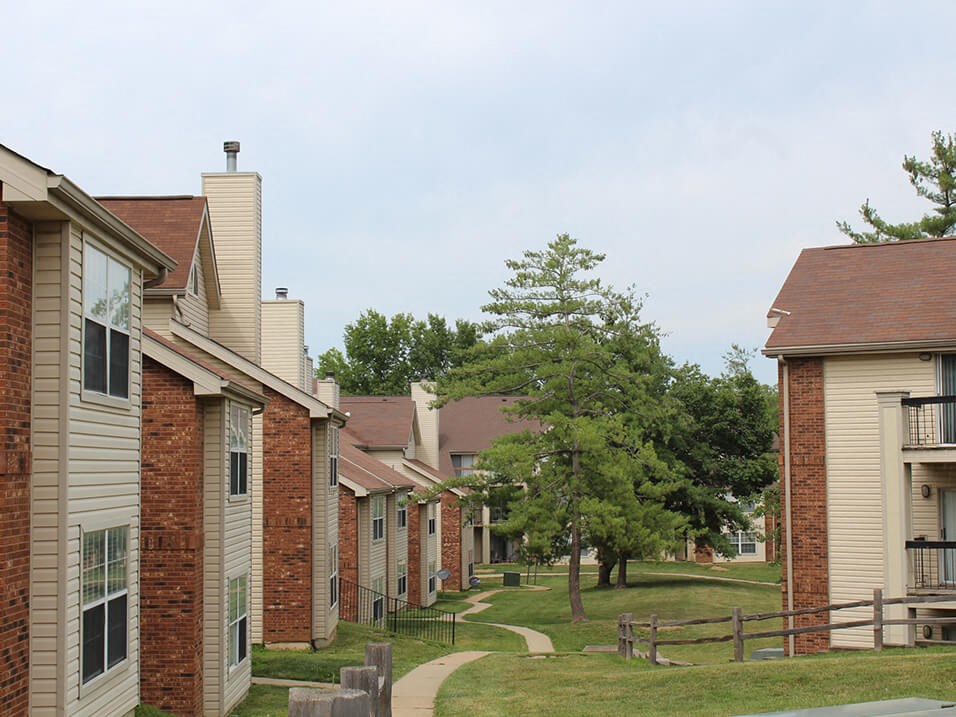 an apartment complex with a grassy area and trees