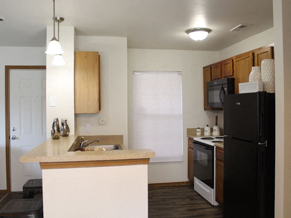 a kitchen with a black refrigerator freezer next to a stove top oven