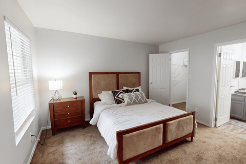 A bedroom with a bed, nightstand, and window.