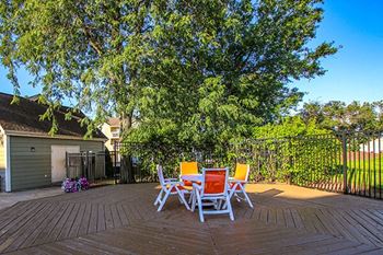 a patio with a table and chairs in front of a fence