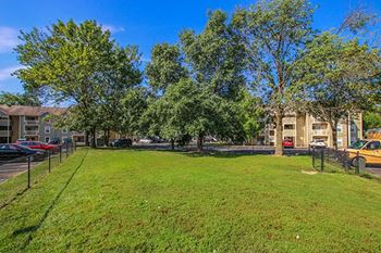 a grassy area with trees and buildings in the background