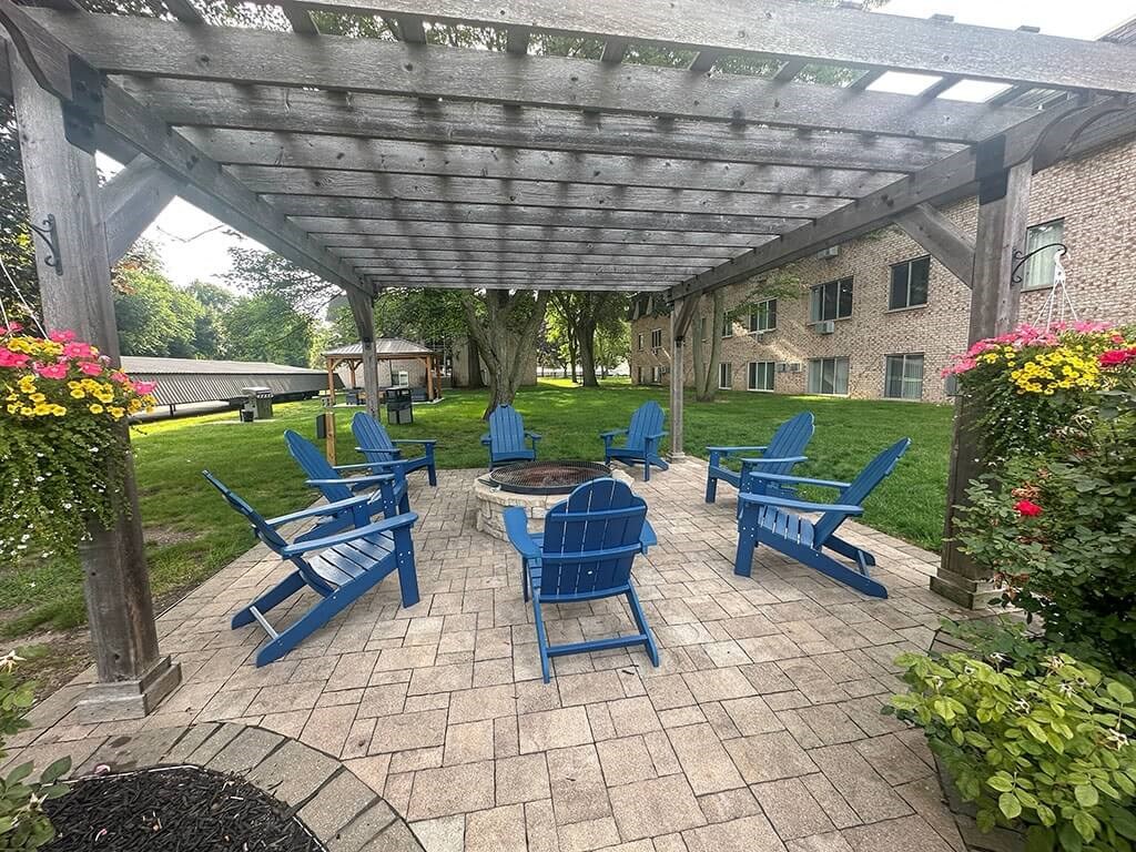 a patio with blue chairs and a fire pit