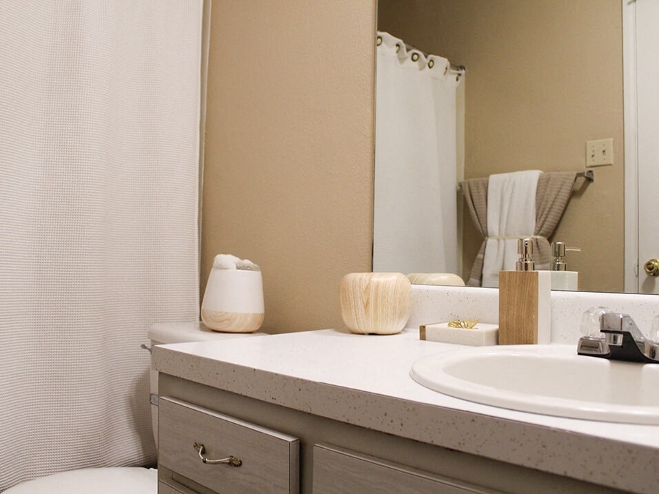 a bathroom with a white sink and toilet next to a white shower curtain