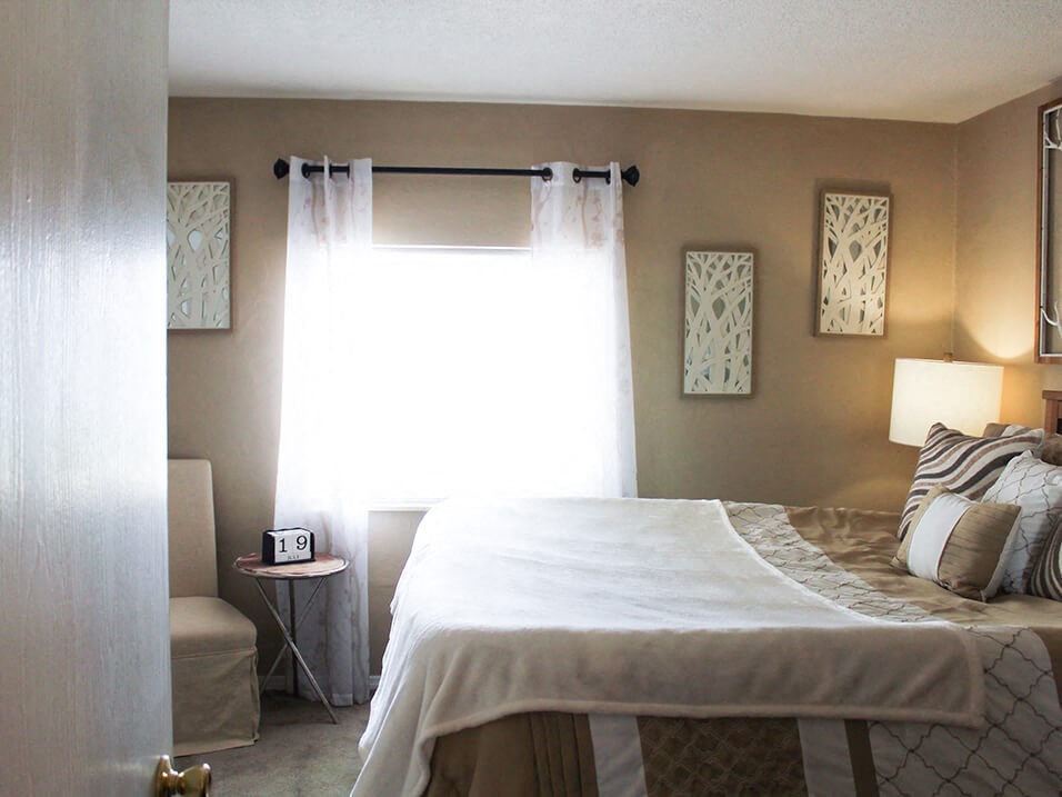 a bedroom with a bed and a chair in front of a window