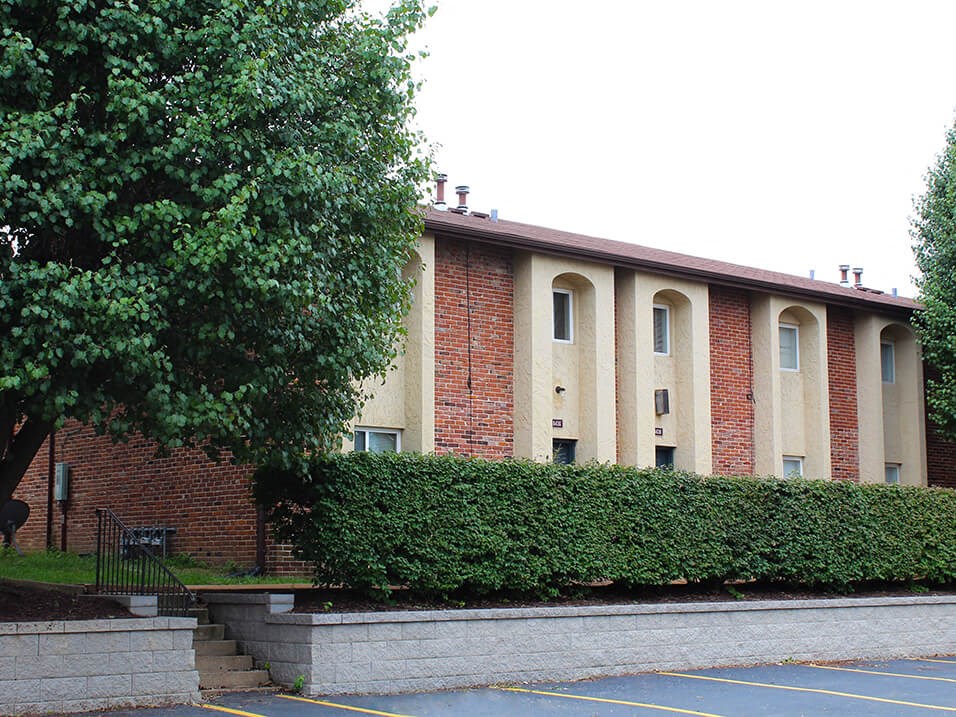 a large brick building with a hedge in front of it