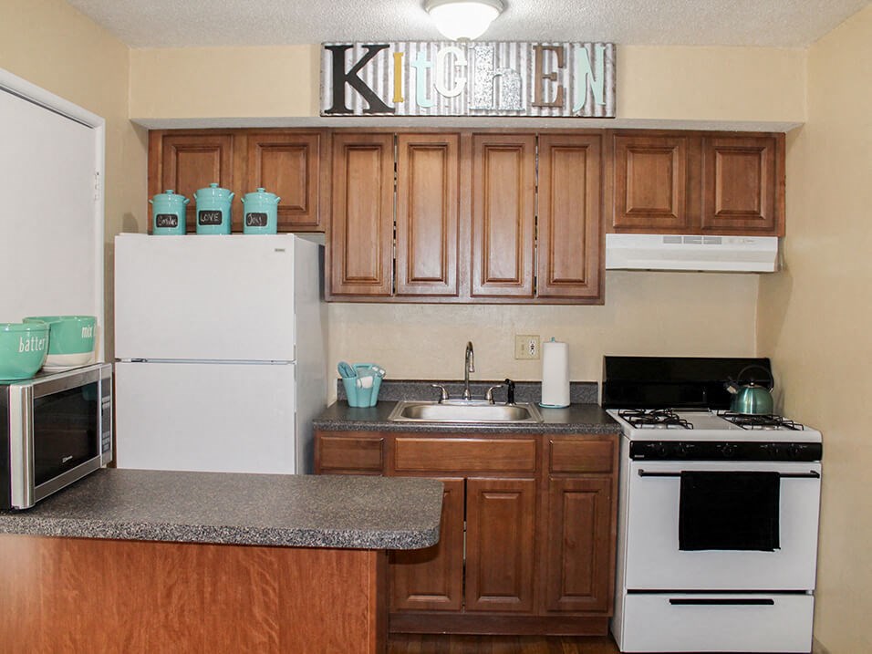 apartment kitchen with wood cabinets and white appliances