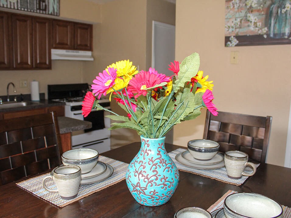 a vase of flowers on a table with plates and cups