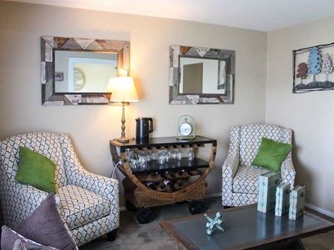 a living room with chairs and a table and a mirror