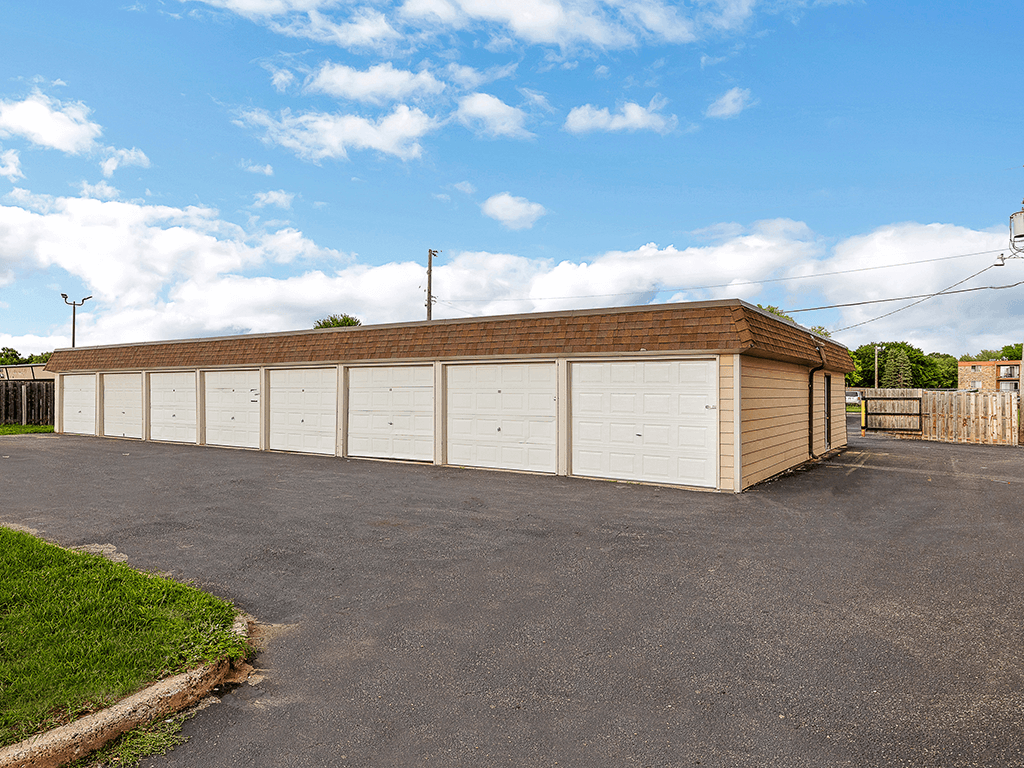 a large white garage with a brick roof on a driveway
