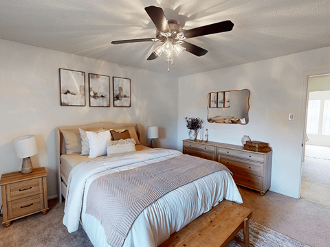 A bedroom with a bed, nightstand, and a ceiling fan.