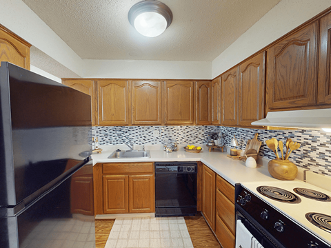 A kitchen with wooden cabinets and a black refrigerator.