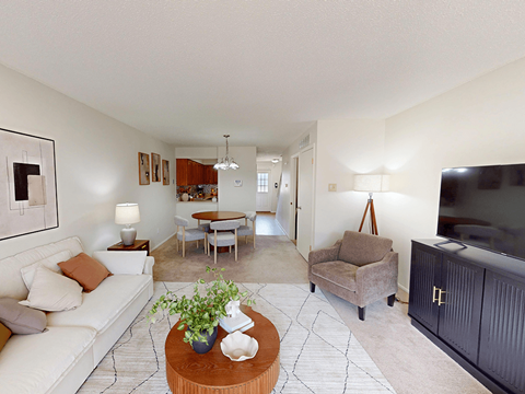 A living room with a white couch and a coffee table with a plant on it.