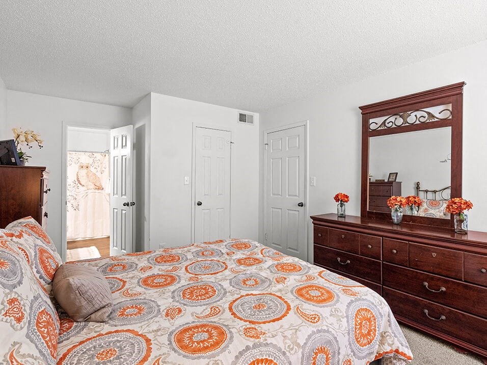 a bedroom with a bed and a dresser and a mirror