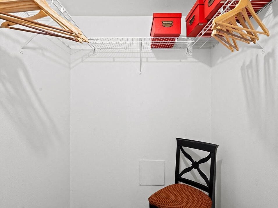 a white closet with a chair and a rack on the wall